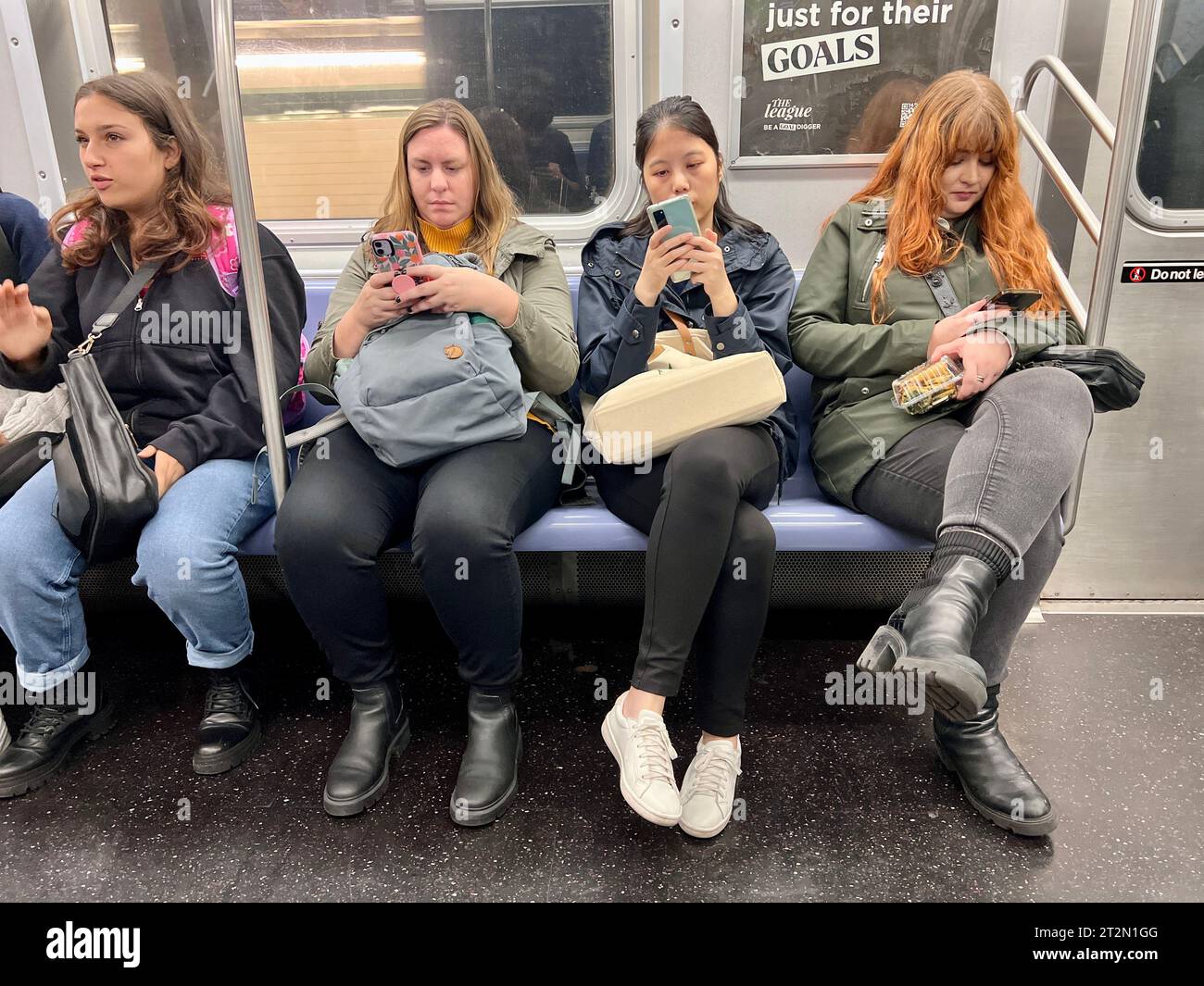 Women occupy their time in transit on a New York City subway train in ...