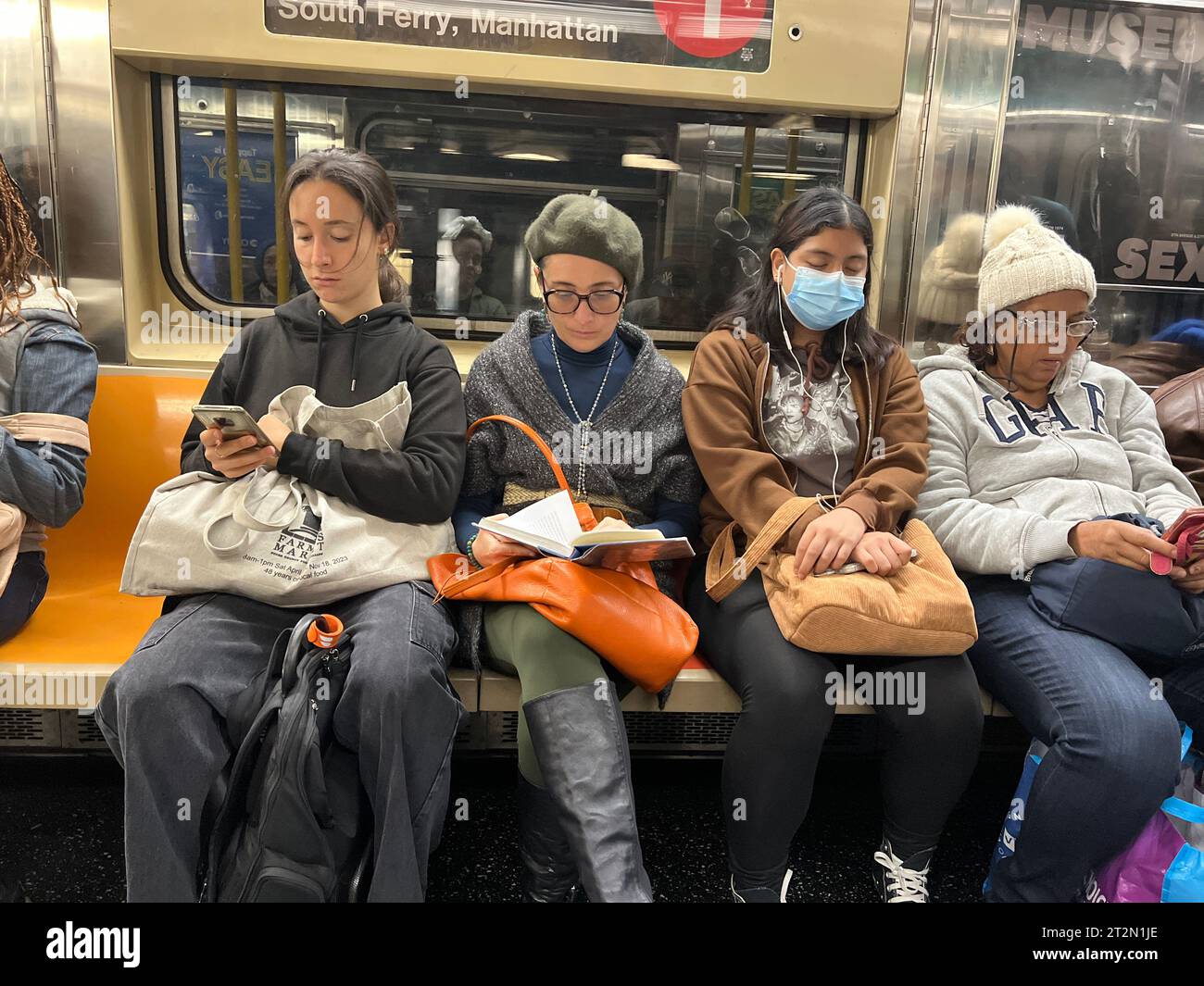 Women occupy their time in transit on a New York City subway train in ...