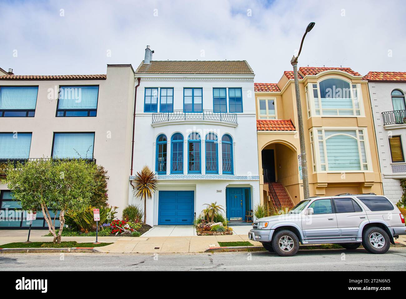 White house with blue trim and blue garage and front door beside other ...