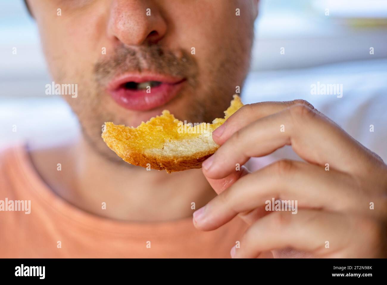 close-up of a man holding a cheese sandwich in his hands in front of his mouth Stock Photo