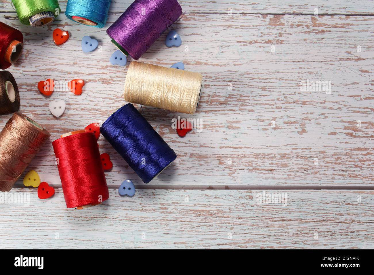 A set of colored threads for sewing clothes, on a wooden background Stock Photo
