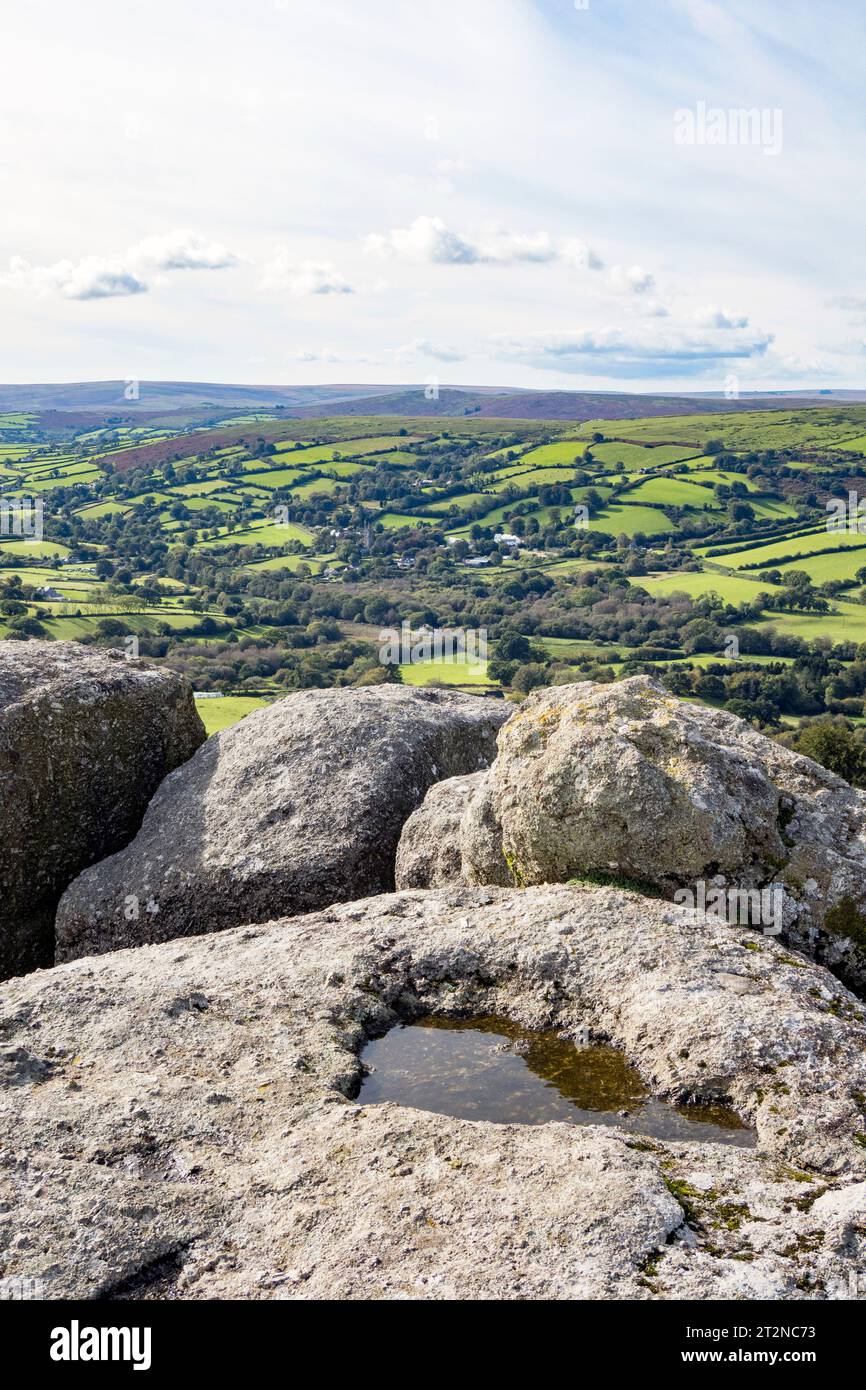UK, England, Devon, Dartmoor National Park. Looking down to Widecombe on the Moor from Bell Tor, on Bonehill Down with a rock basin on summit. Stock Photo