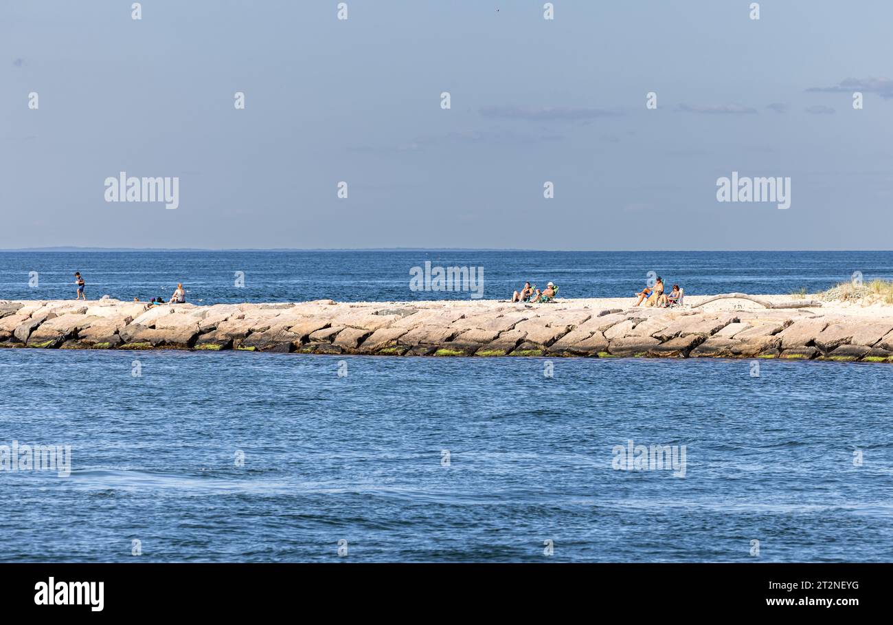 people sun bathing on the break water at gin beach Stock Photo