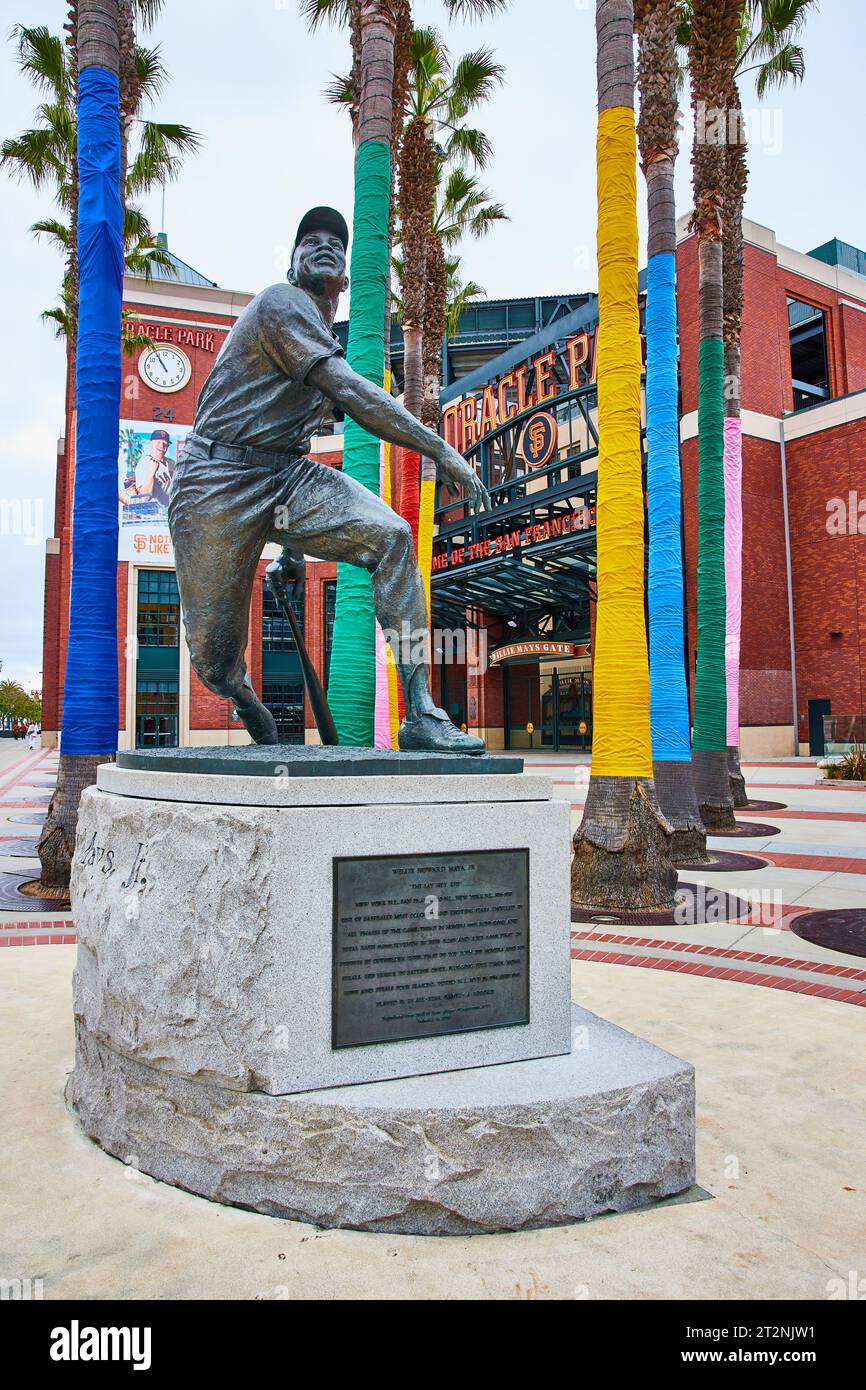 Willie Mays statue with colorful palm trees behind it with Oracle Park