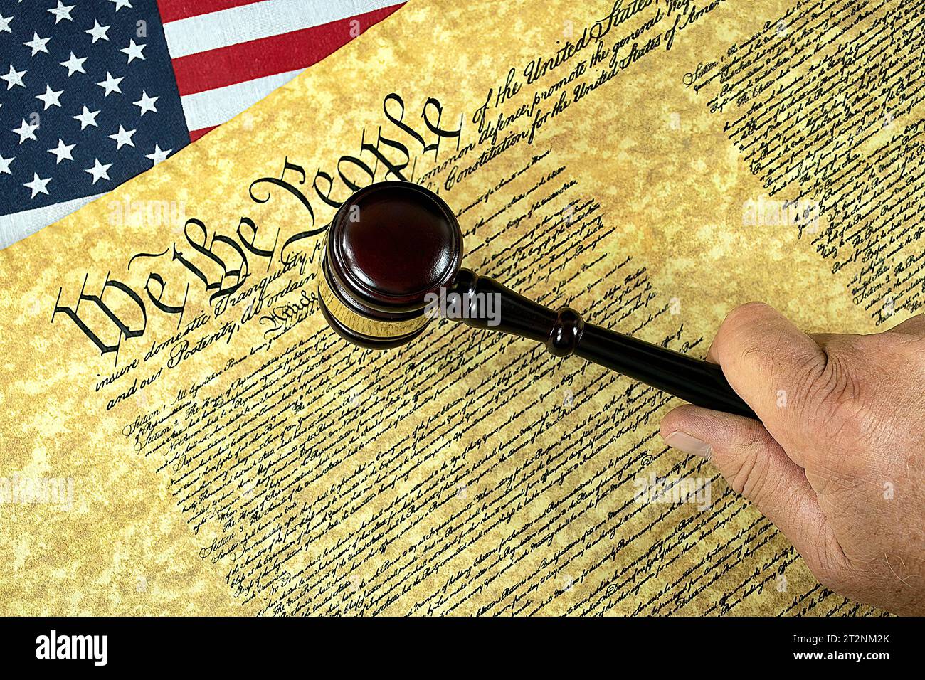 Man's hand holding a judicial gavel on the U.S. Constitution document and American flag Stock Photo