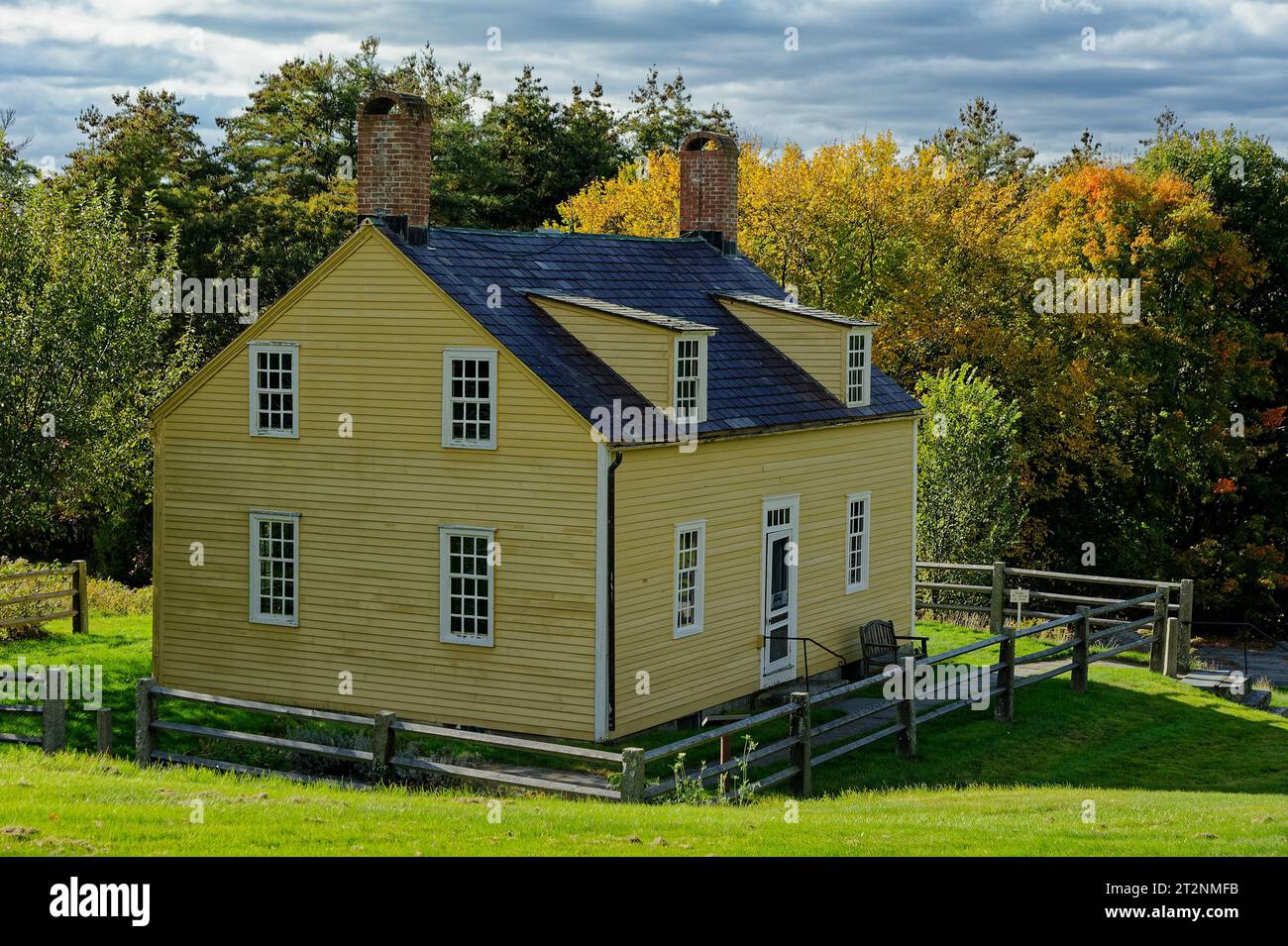 The yellow exterior of the 1920's Shaker house from the nearby Harvard