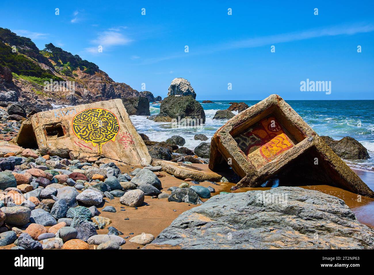 Colorful rocks around graffiti covered concrete fragments washed ashore ...