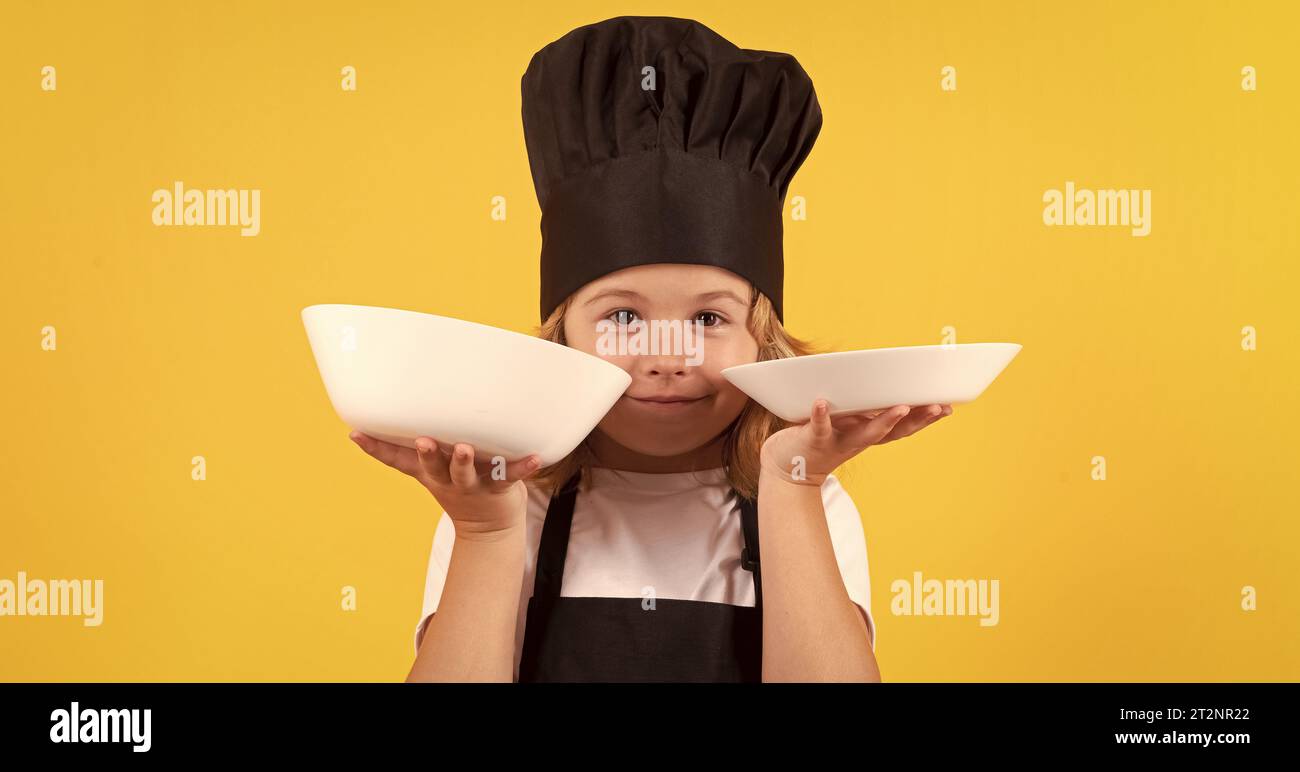 Little cook with cooking plate. Portrait of little child in uniform of cook. Chef boy isolated on studio background. Cute child to be a chef. Child dr Stock Photo