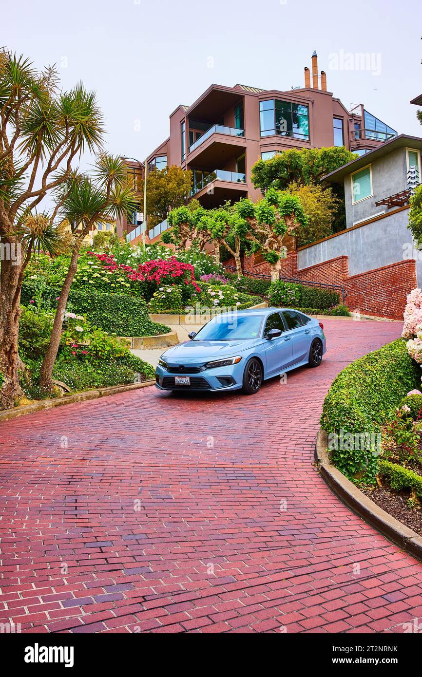 Expensive car driving down Lombard Street with red brick road and fancy