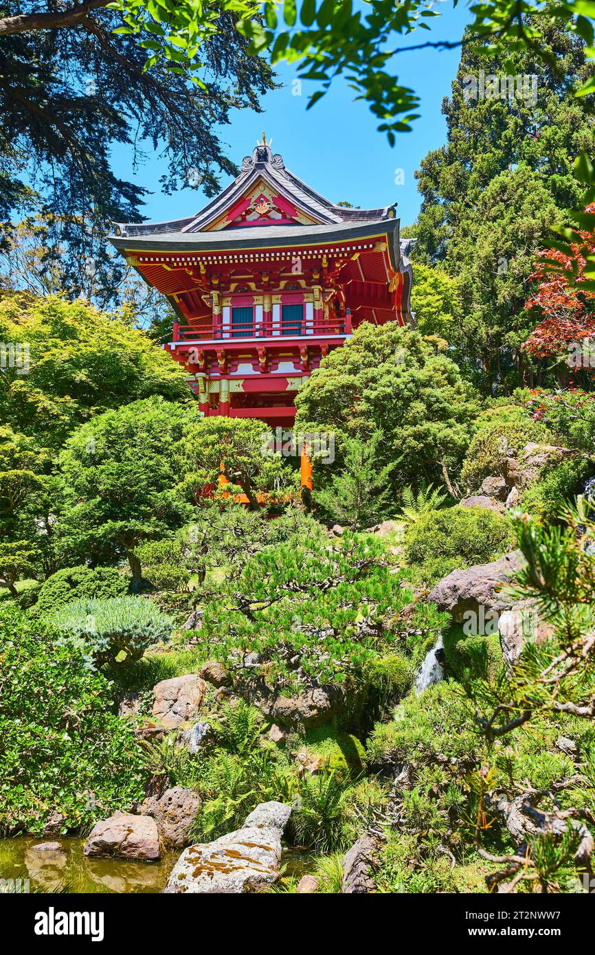 Red Pagoda nestled among green trees with blue sky overhead Stock Photo ...
