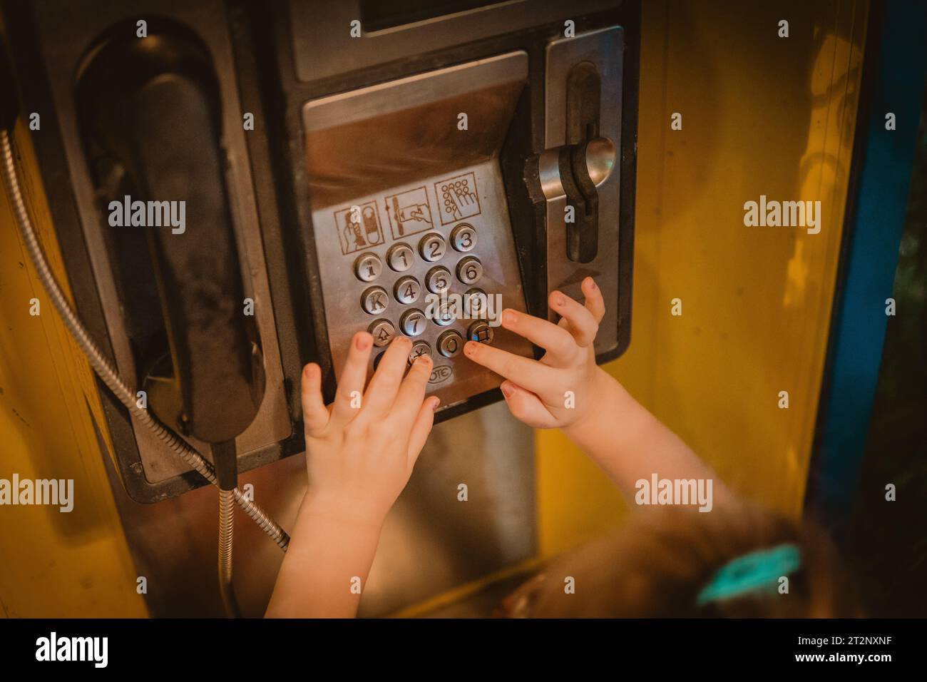 Little girl typing numbers on phone booth Stock Photo