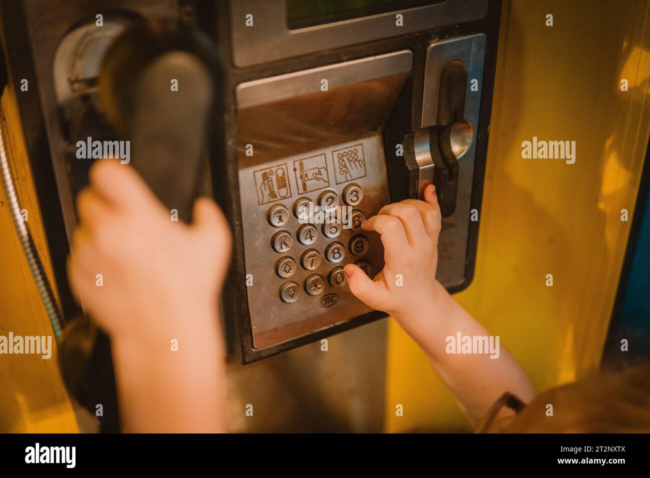 Little girl typing numbers on phone booth Stock Photo