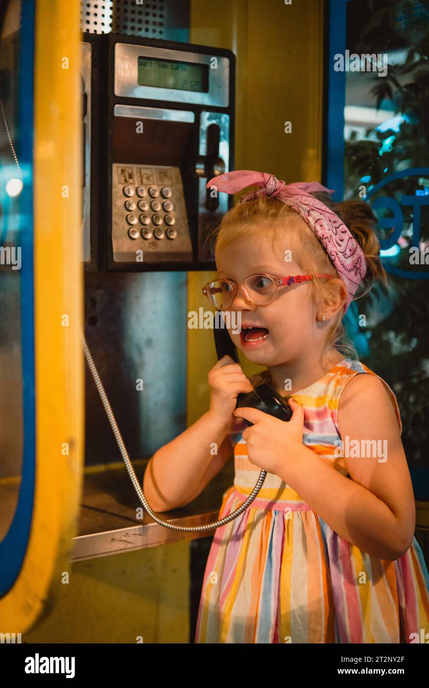 Little girl on a retro phone booth Stock Photo