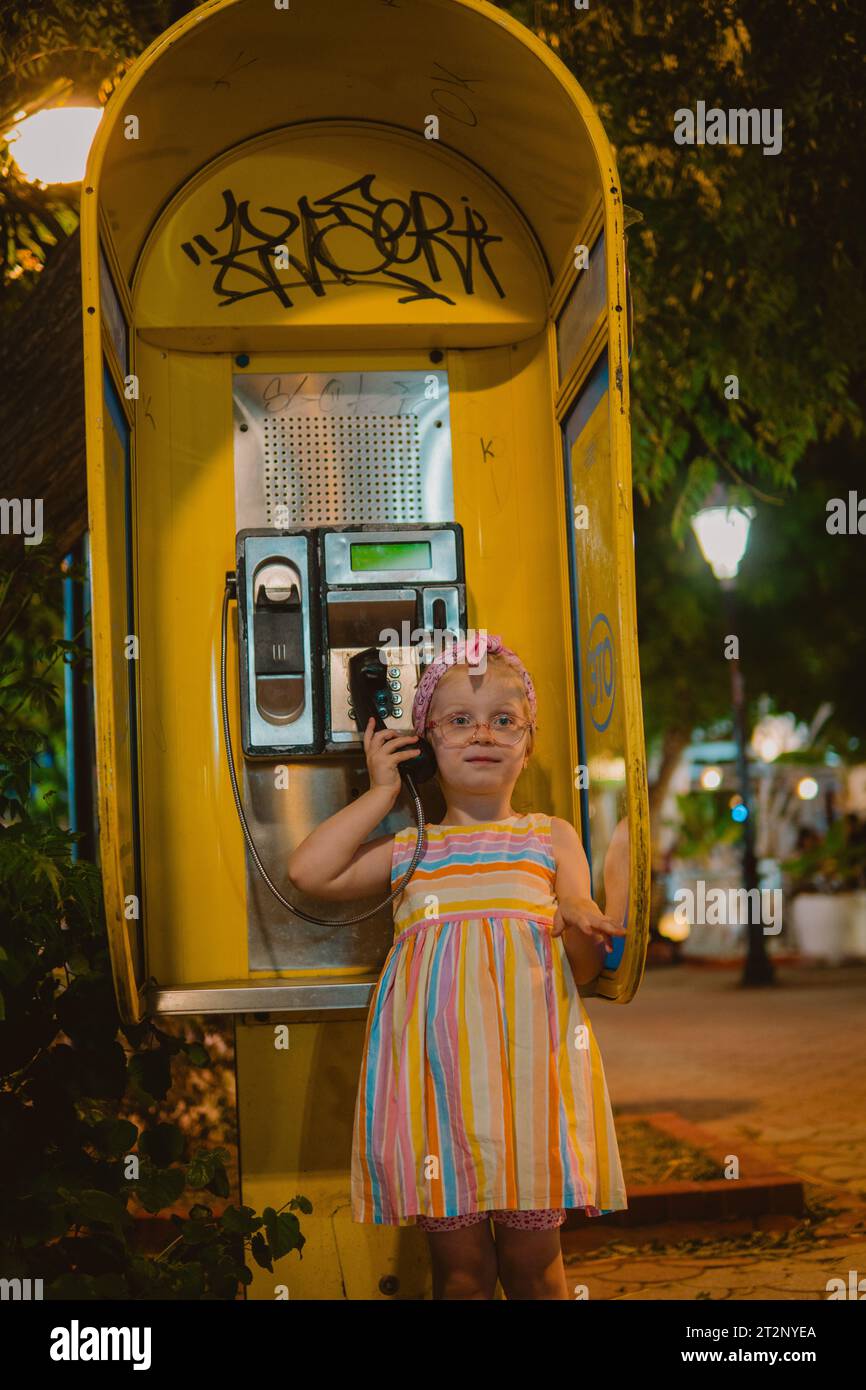 Little girl on a retro phone booth Stock Photo