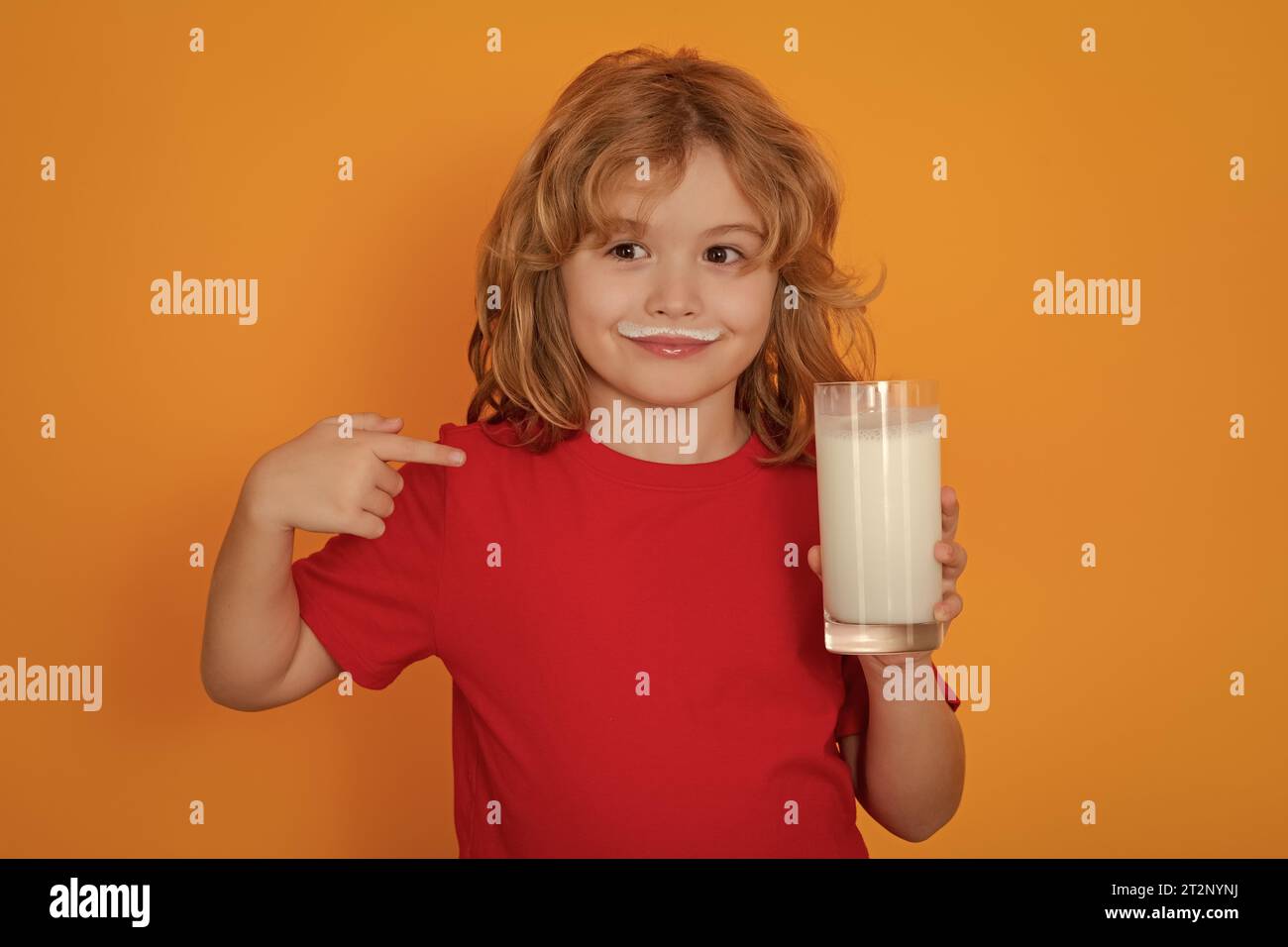 Healthy food for kids. Organic milk. Cute little child with glass of milk on studio color background. Kid with milk moustache. Fun portrait of cute ki Stock Photo