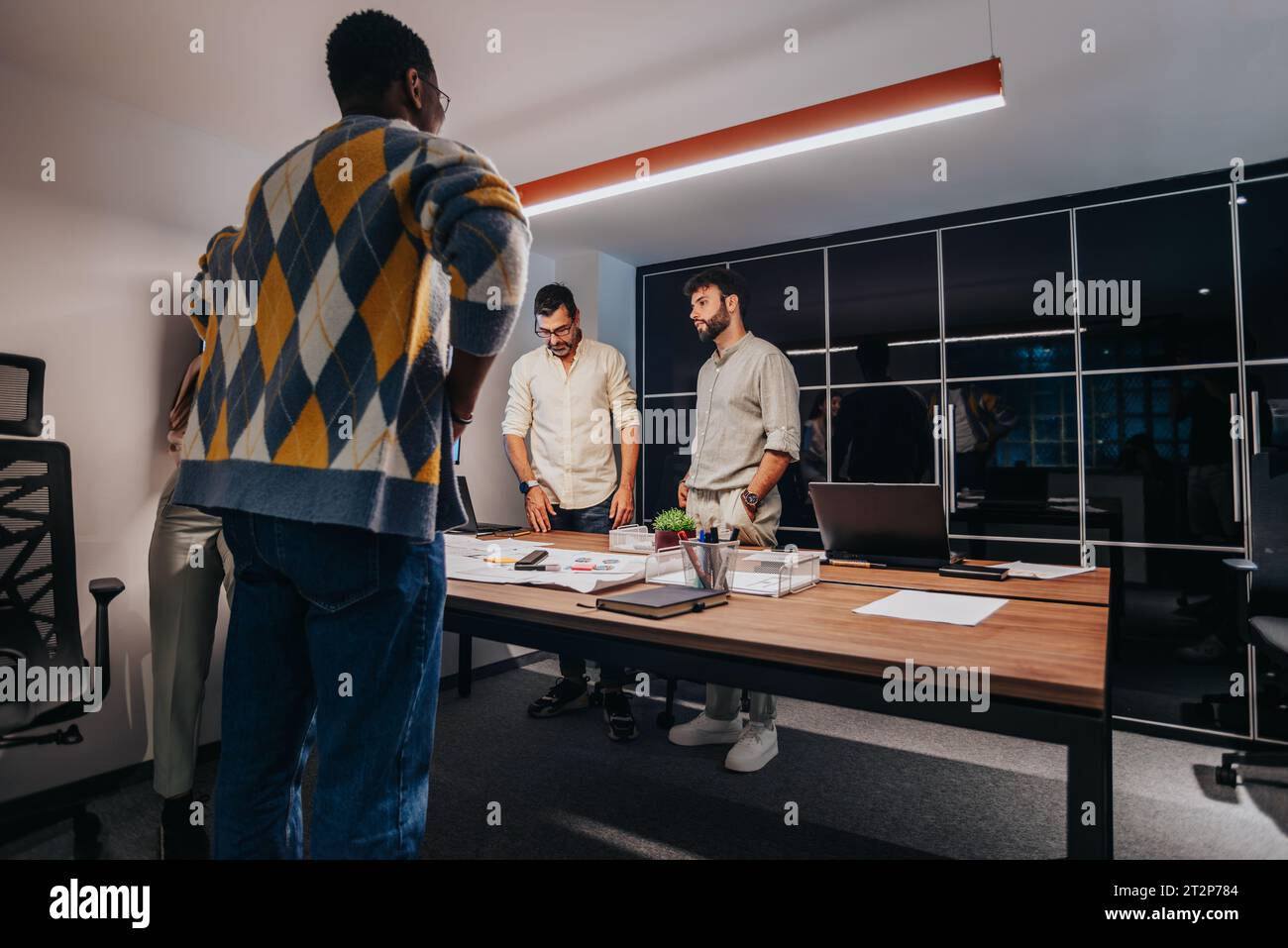 A diverse team of architects and business professionals collaborate in a boardroom, discussing a blueprint for a project. Stock Photo