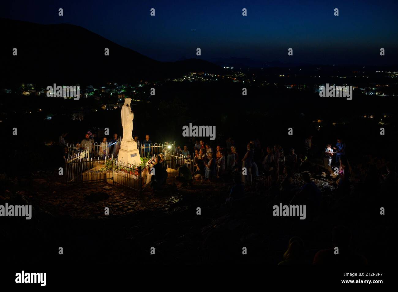 Statue of the Virgin Mary, the Queen of Peace, on Mount Podbrdo at night surrounded by praying pilgrims. Medjugorje, Bosnia and Herzegovina. Stock Photo