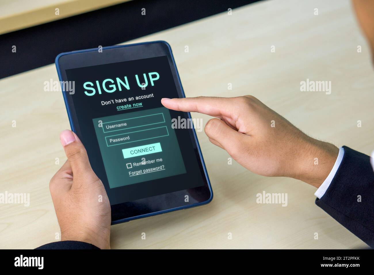 Digital Life Exploration. A focused businessman in black suit engrossed in creating his identity online, registering for an account on his tablet comp Stock Photo