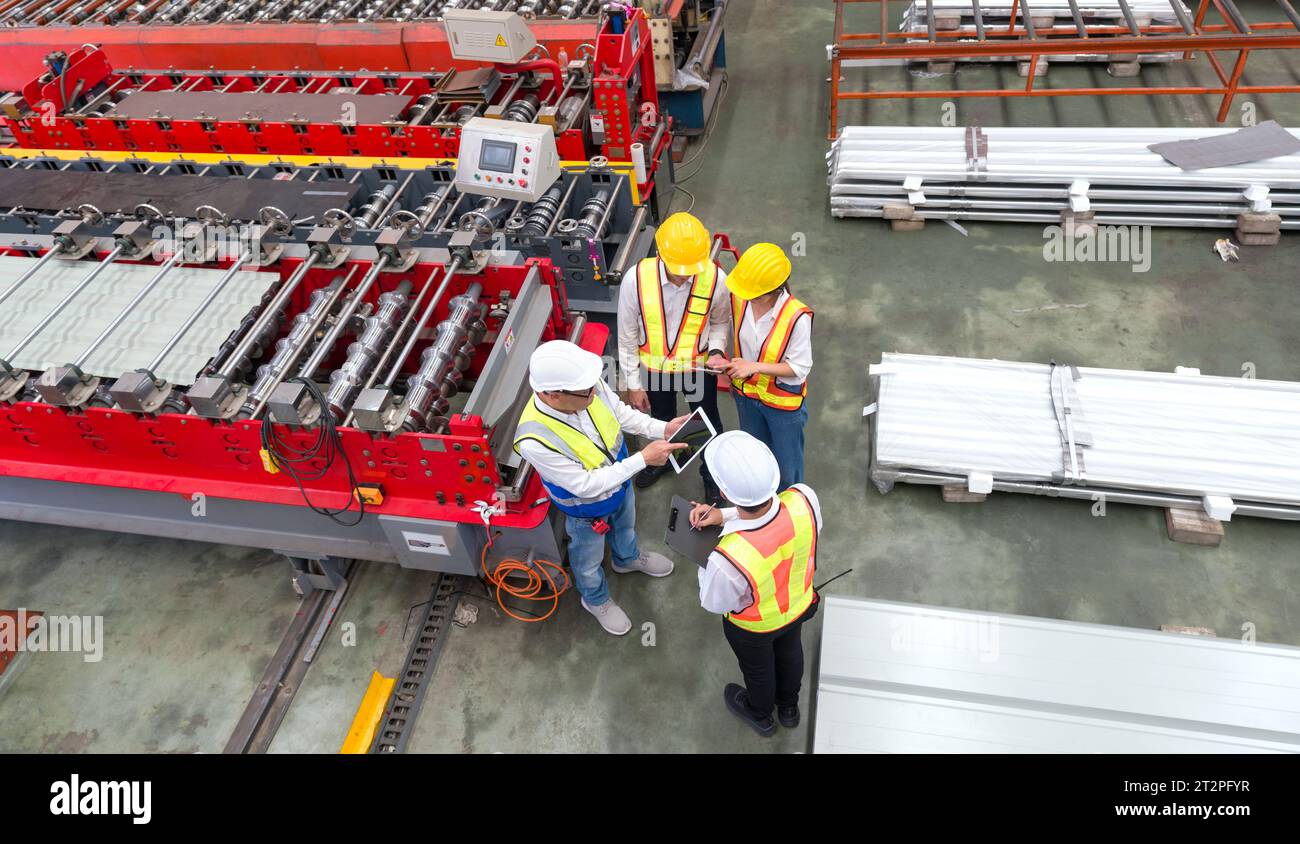 Senior engineer manager trains new employees within the metal sheet factory. Everyone wear