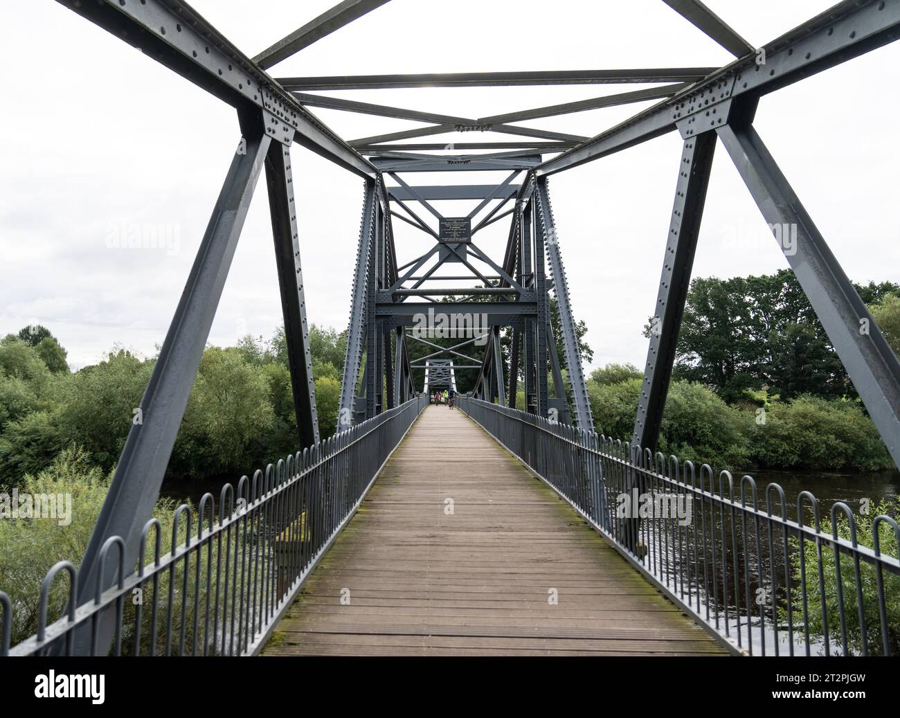 walking across a steel foot bridge across the River Eden, near Carlisle, Cumbria Stock Photo