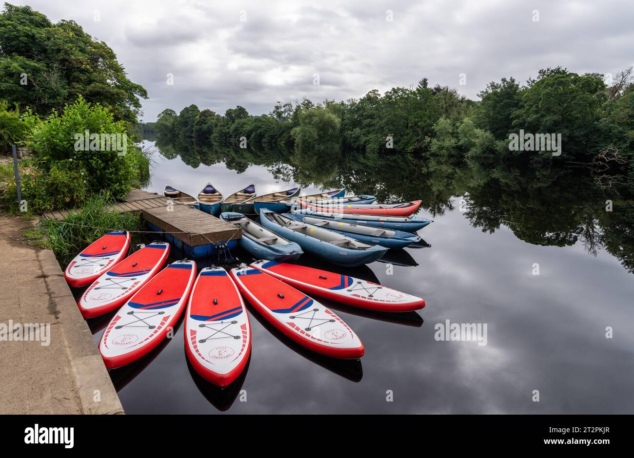 paddleboards and canoes tied up along the River North Tyne at Chollerford, Northumberland, UK Stock Photo