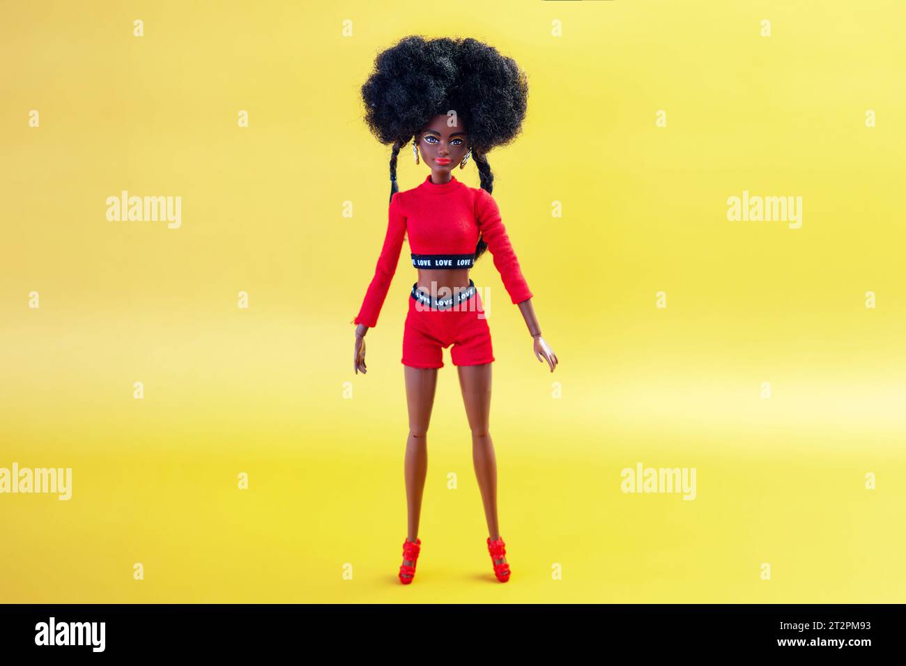 October 9, 2023. Barnaul, Russia: african american Barbie doll with black hair in a red suit standing on a yellow background. Stock Photo