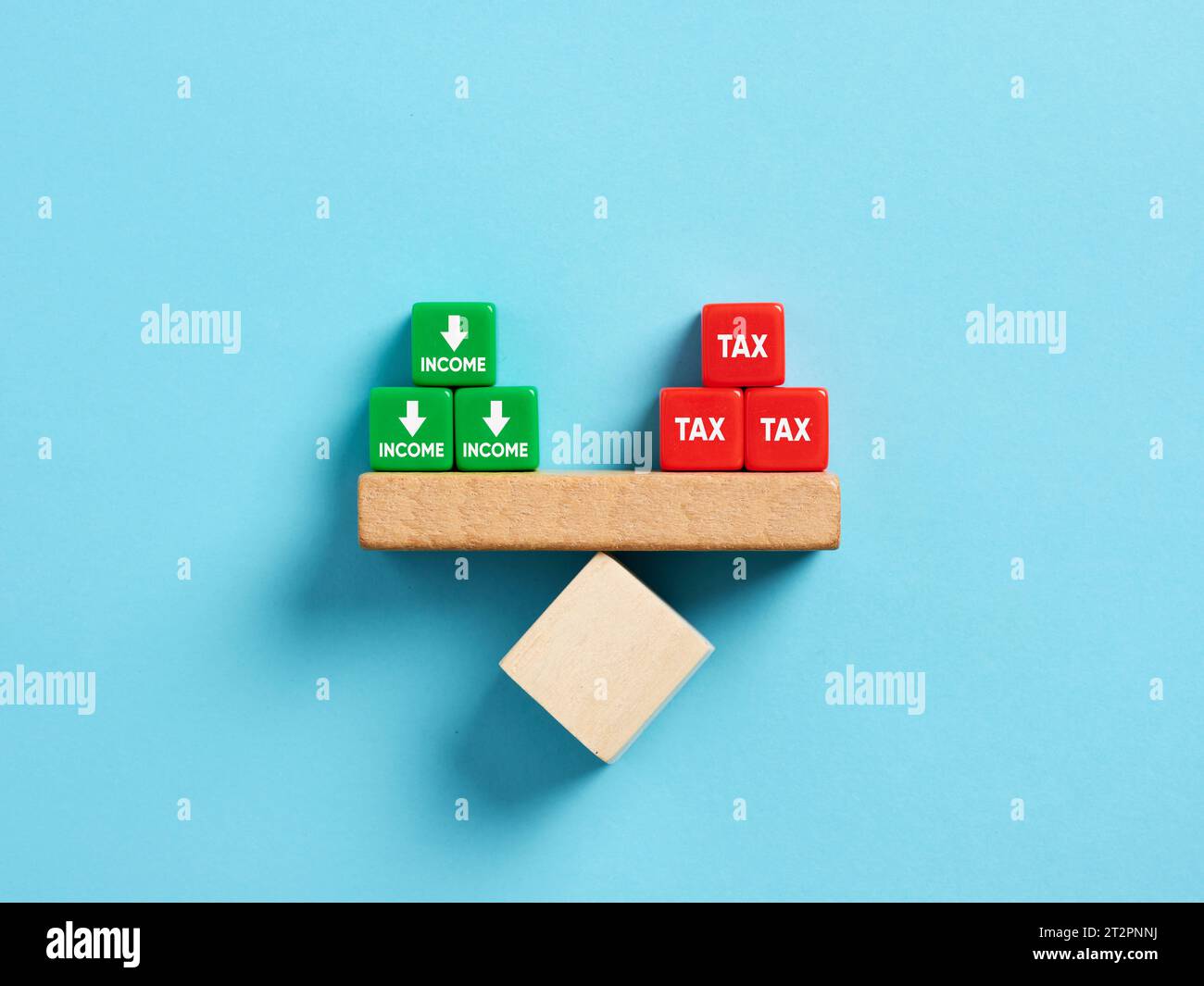Income tax concept. Tax and decreasing income. The words tax and income on balance on a scale seesaw. Stock Photo