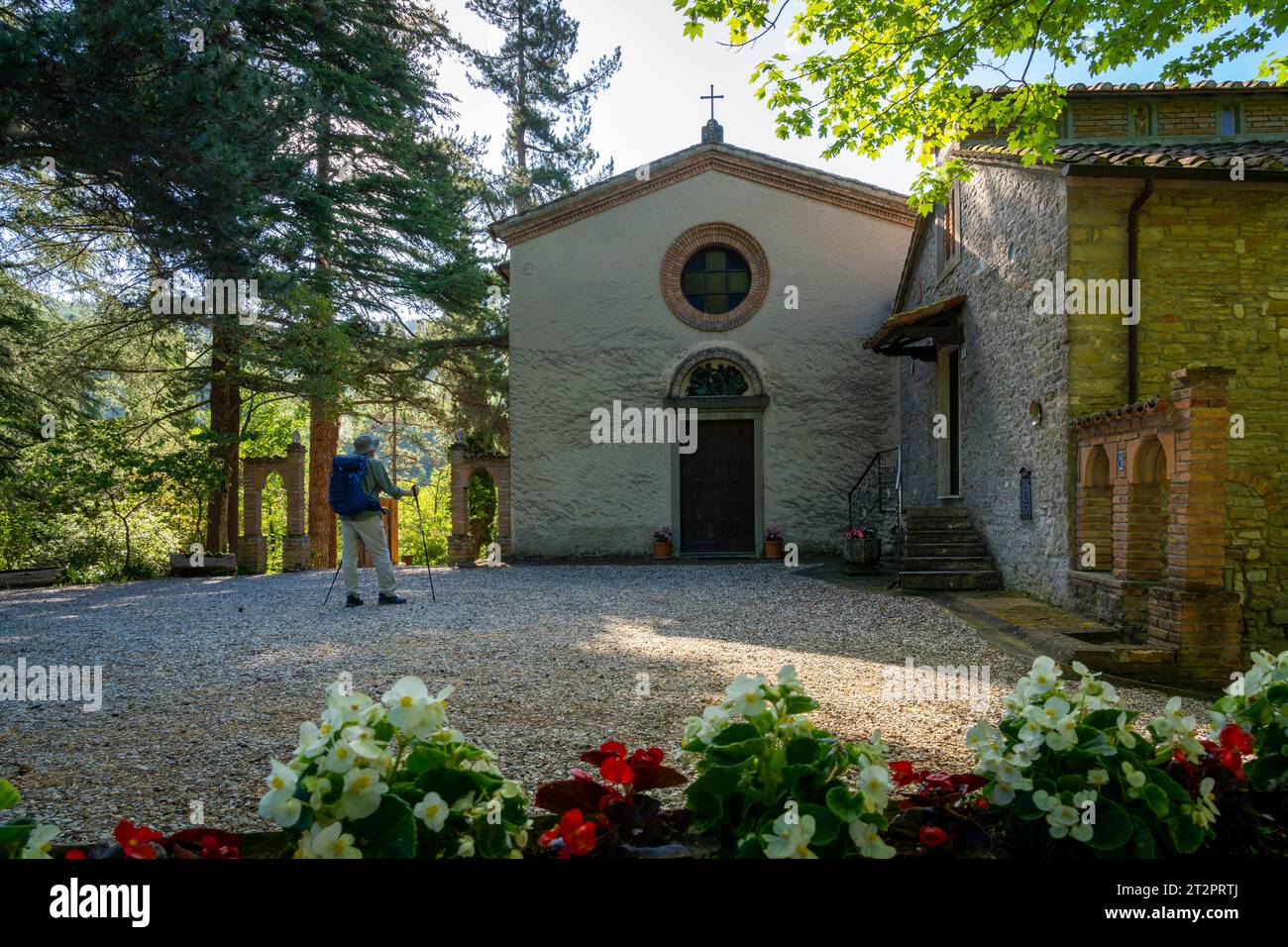 Man with backpack admiring a church in the apennines. Santa Reparata, Modigliana, Forlì, Emilia Romagna, Italy, Europe. Stock Photo