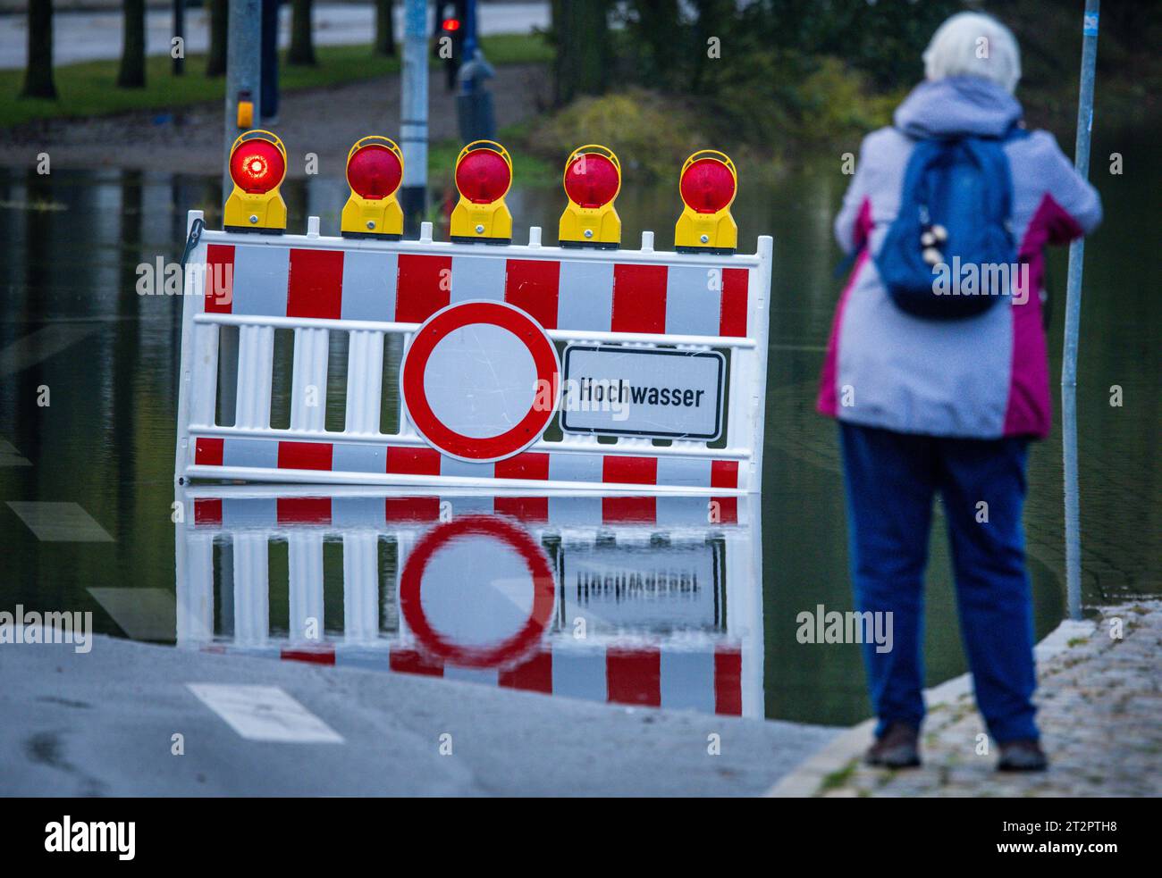 Wismar, Germany. 21st Oct, 2023. A woman takes a photo of a flooded street near the city harbor. After the storm surge, streets and squares are still under water in the shore area. Credit: Jens Büttner/dpa/Alamy Live News Stock Photo
