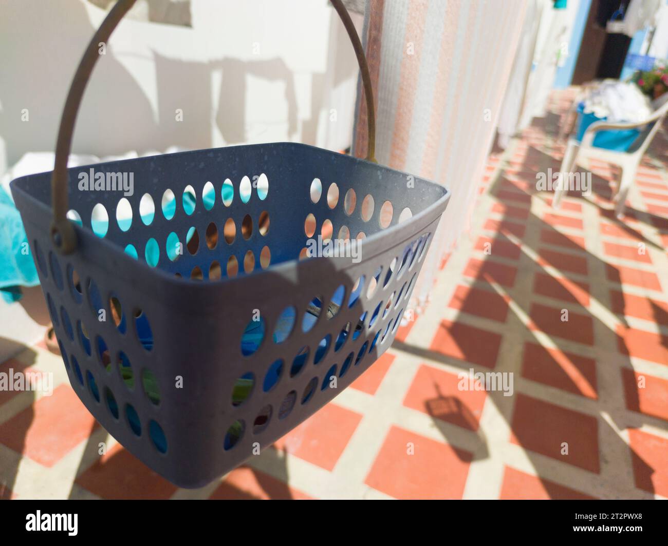 Clothespins basket hanging from washing line at sunny courtyard. Selective focus Stock Photo