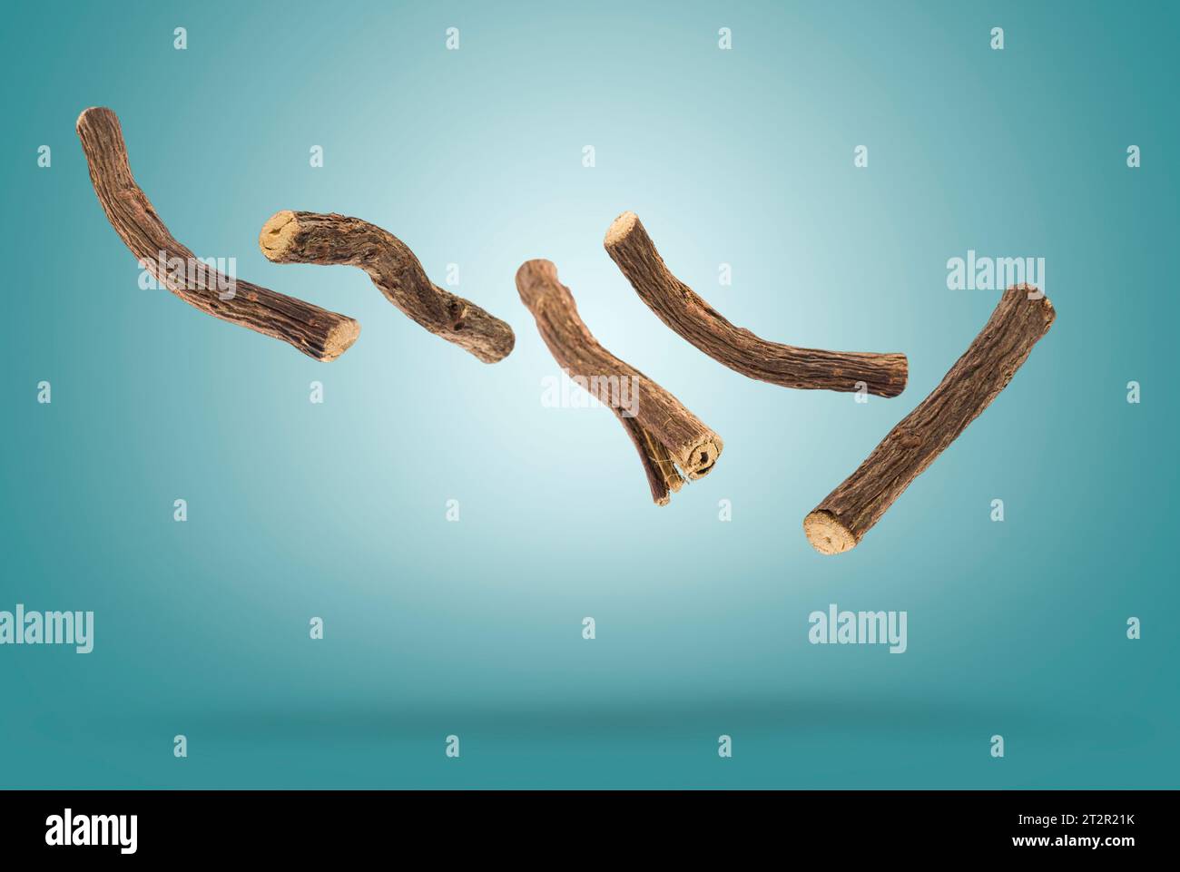 Sticks of liquorice root floating on blue background. Stock Photo