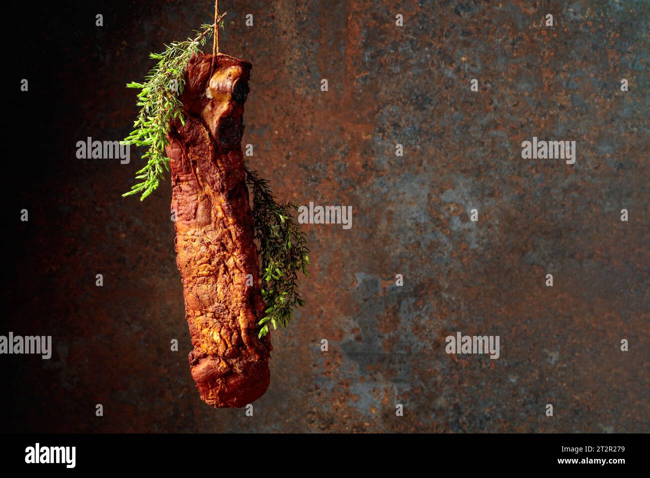 Homemade smoked pork ribs with juniper branches on a rusty background ...