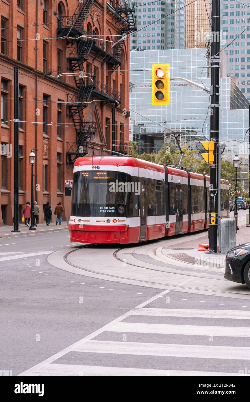 Toronto, Canada, vertical image of a Bombardier Flexity Outlook streetcar or tram train turning by the Flatiron or Gooderham building in the old town Stock Photo