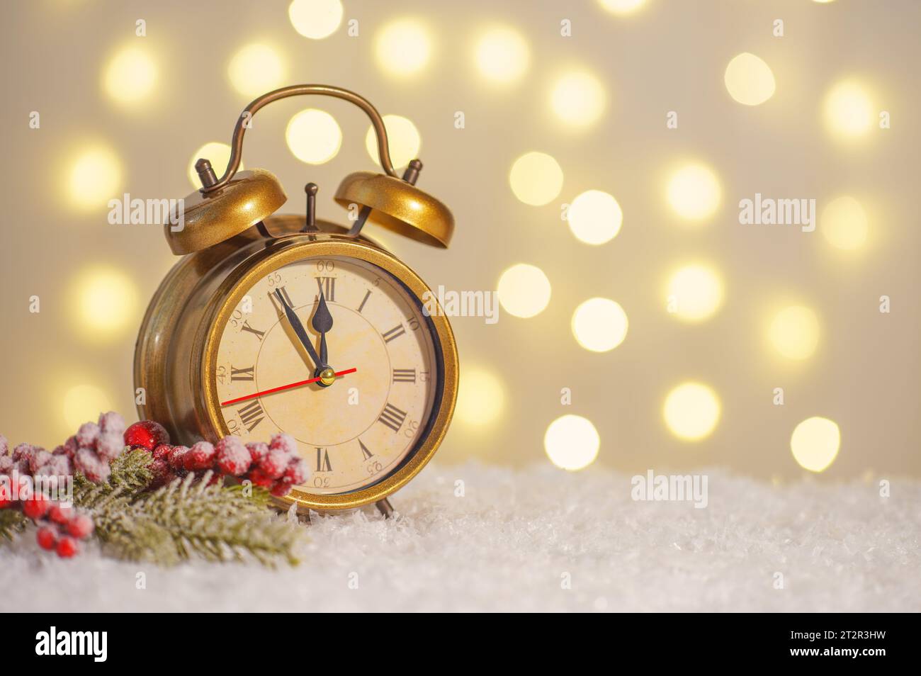 Bronze alarm clock and decorative Christmas tree branch on snow and glowing lights bokeh background. Christmas, New Year greeting card with copy space Stock Photo