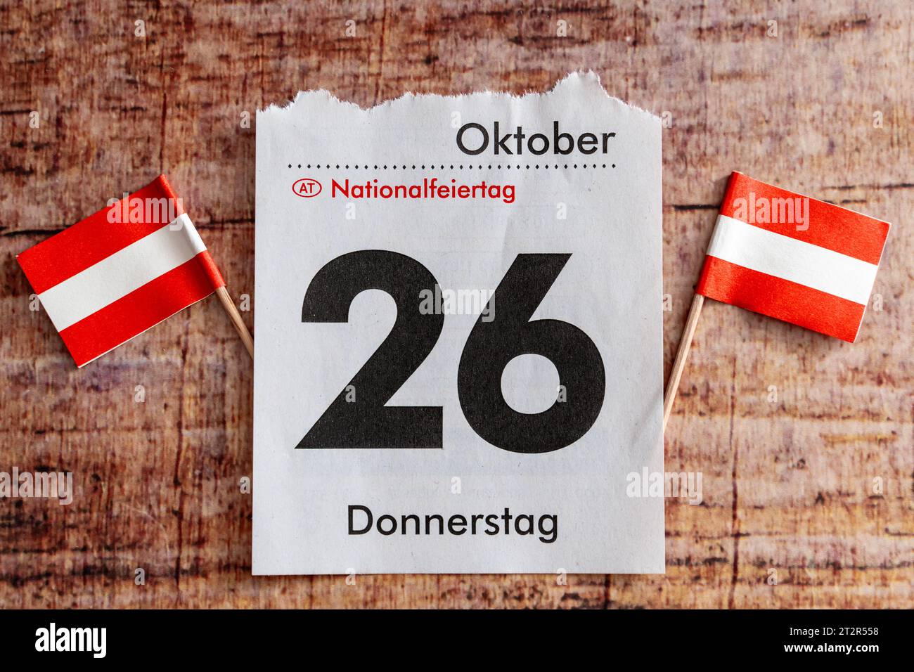 21 October 2023: Calendar page with October 26, national holiday in Austria together with two Austrian flags on a wooden table *** Kalenderblatt mit dem 26. Oktober, Nationalfeiertag in Österreich zusammen mit zwei österreichischen Flaggen auf einem Holztisch Stock Photo