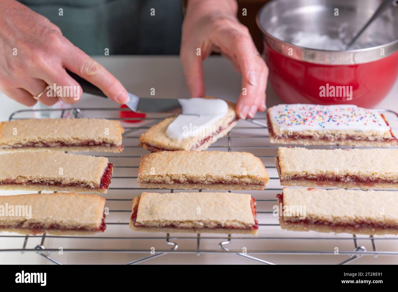 Spreading icing on butter cookies before adding sprinkles Stock Photo