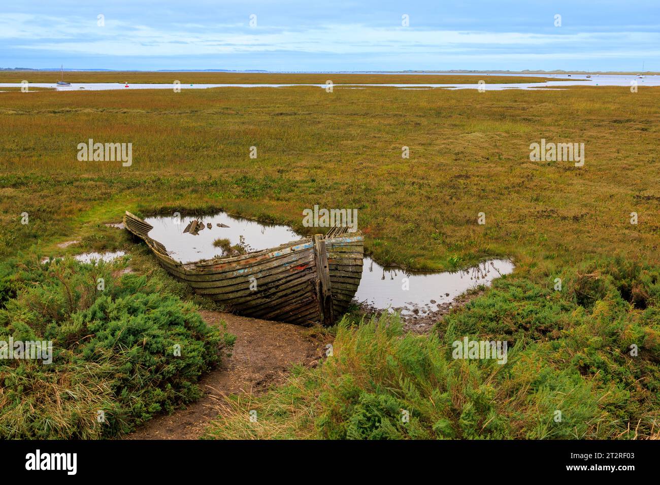 A decaying wooden boat rotting in the salt marshes at Blakeney, Norfolk, England, UK Stock Photo