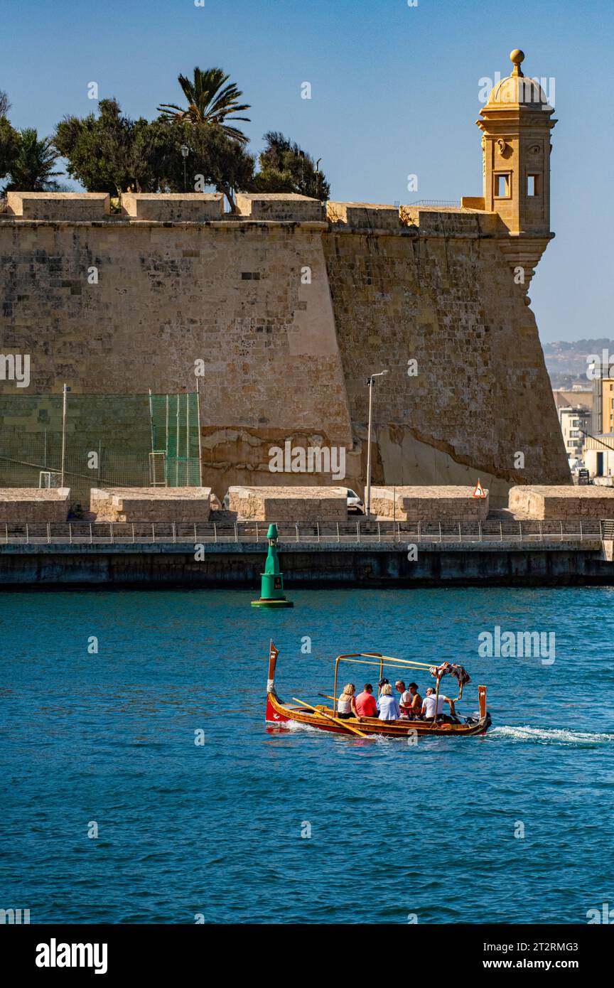 The Maltese Dghajsa (similar to a gondola) transports passengers from Valletta to Senglea with the Gardjola Gardens in the background. Stock Photo