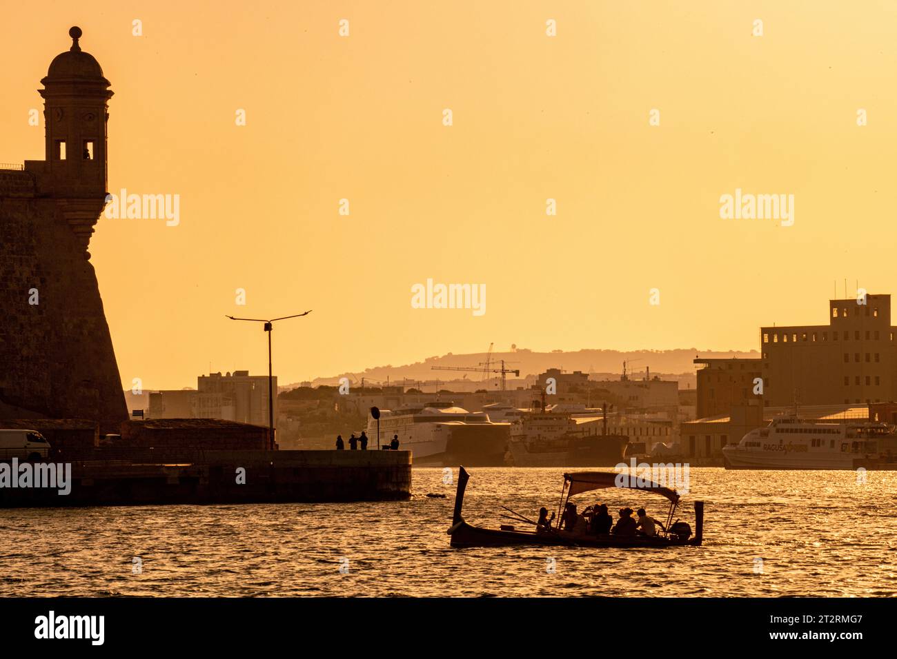 The Maltese Dghajsa (similar to a gondola) transports passengers between Valletta and Birgu in Malta as the sun sets Stock Photo