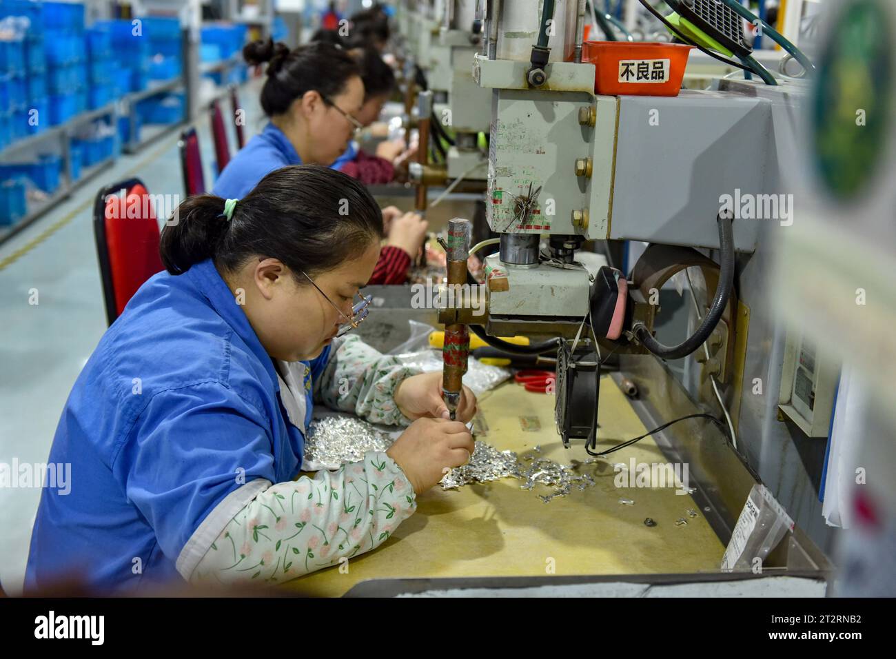 Women wearing blue overalls work on the assembly line of a factory that produces electrical equipment. China's gross domestic product grew by 4.9 percent year-on-year in the third quarter after a 6.3 percent rise in the second quarter, posting a steady recovery despite downward pressures, the National Bureau of Statistics said on Wednesday. In the first three quarters, China's GDP grew by 5.2 percent to 91.3 trillion yuan ($12.5 trillion) after a 5.5 percent growth in the first half of the year, the bureau said. (Photo by Sheldon Cooper/SOPA Images/Sipa USA) Stock Photo