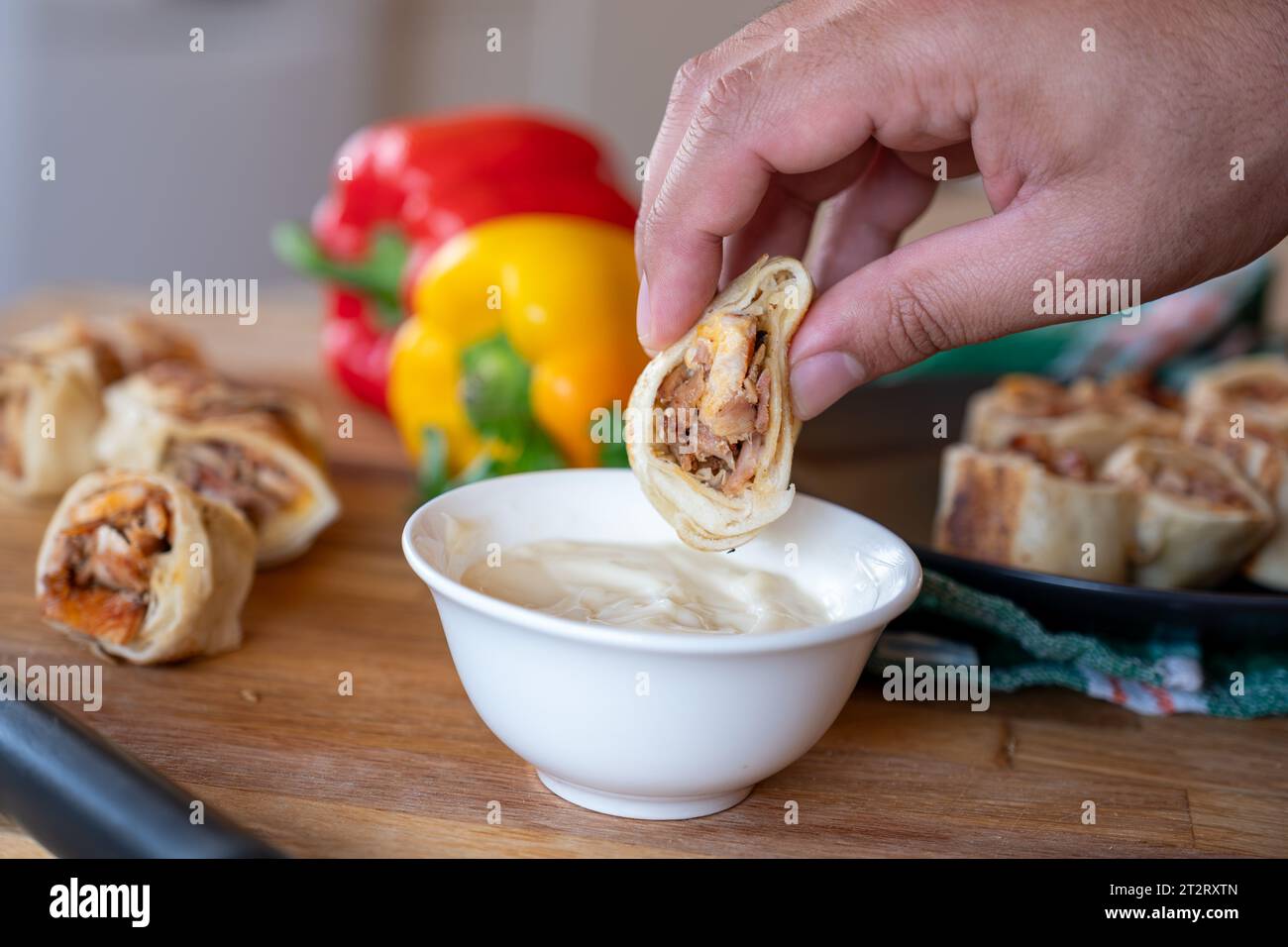hand holding shawarma piece and dip it in mayonnaise or garlic tahini