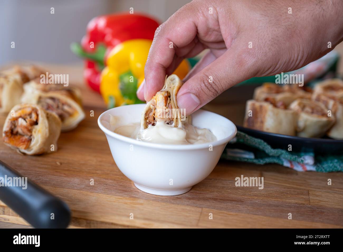 hand holding shawarma piece and dip it in mayonnaise or garlic tahini