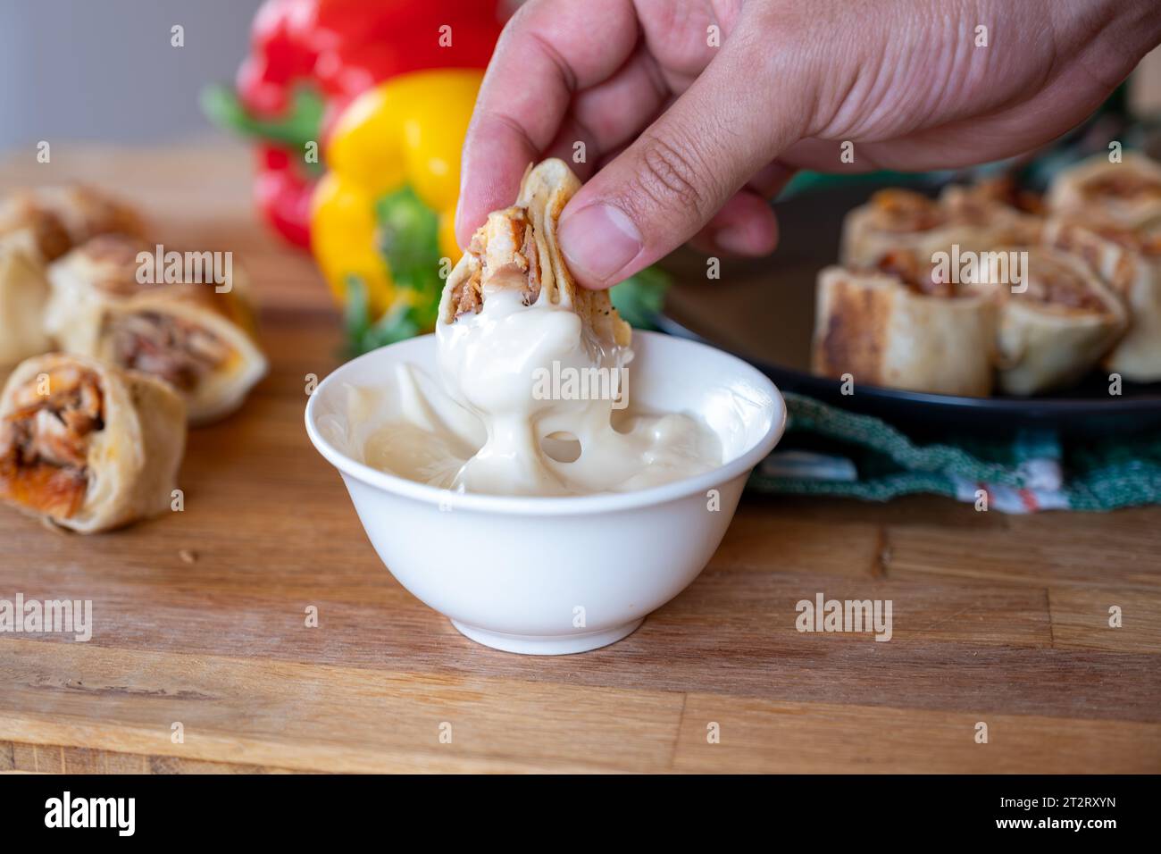 hand holding shawarma piece and dip it in mayonnaise or garlic tahini