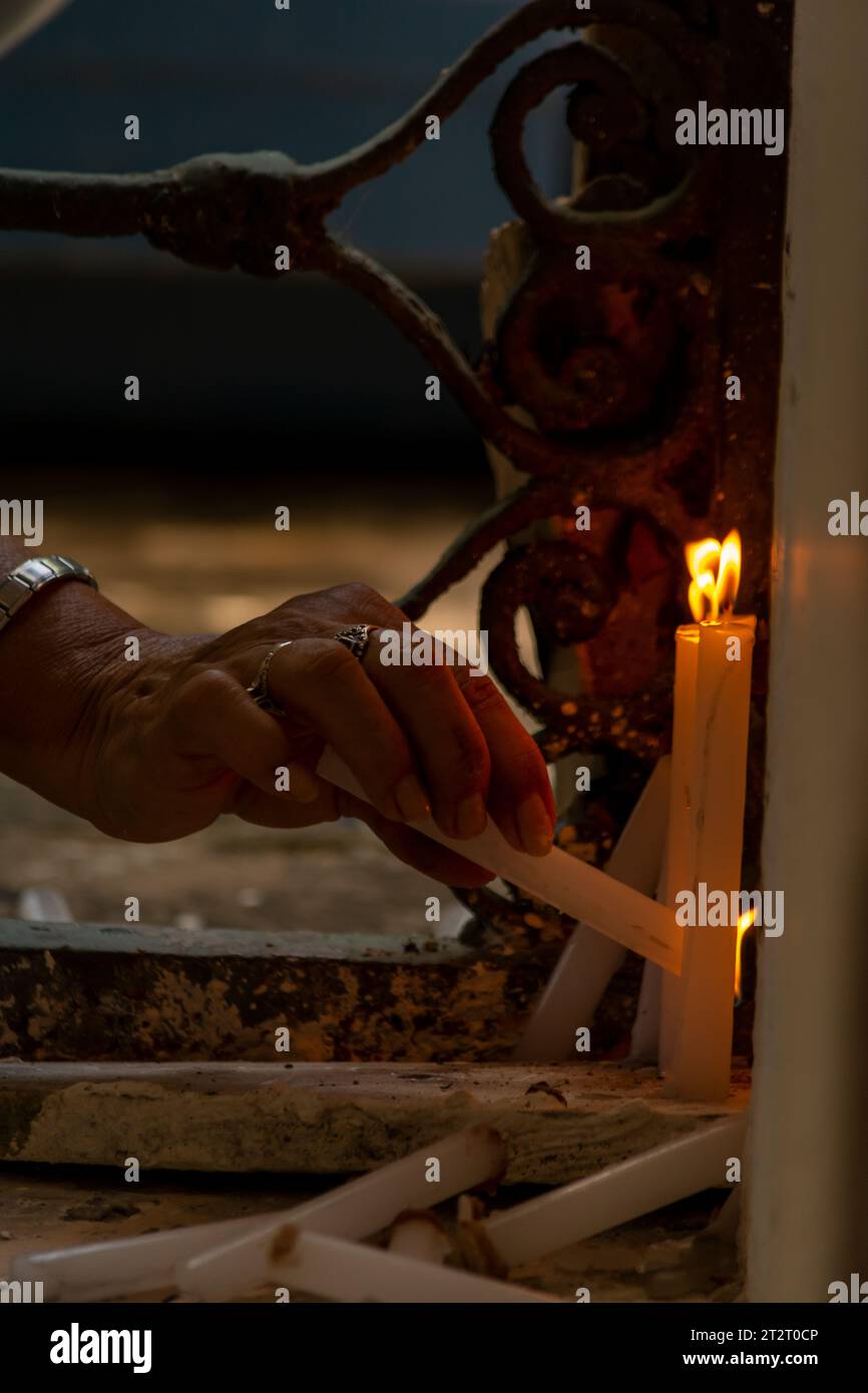 Candles being lit by a human hand. Religious request concept. yellow candlelight Stock Photo Alamy