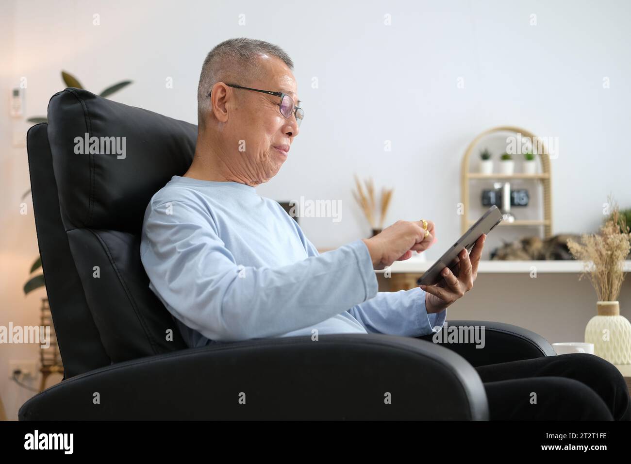 Senior Asian men at the sofa couch using smartphone tablet for browsing internet and reading news online in the morning.. Stock Photo