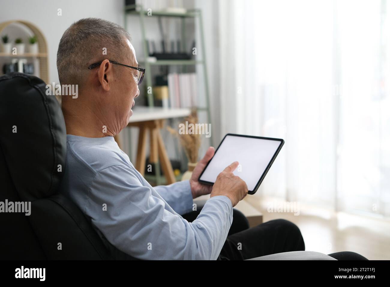 Senior Asian men at the sofa couch using smartphone tablet for browsing internet and reading news online in the morning.. Stock Photo