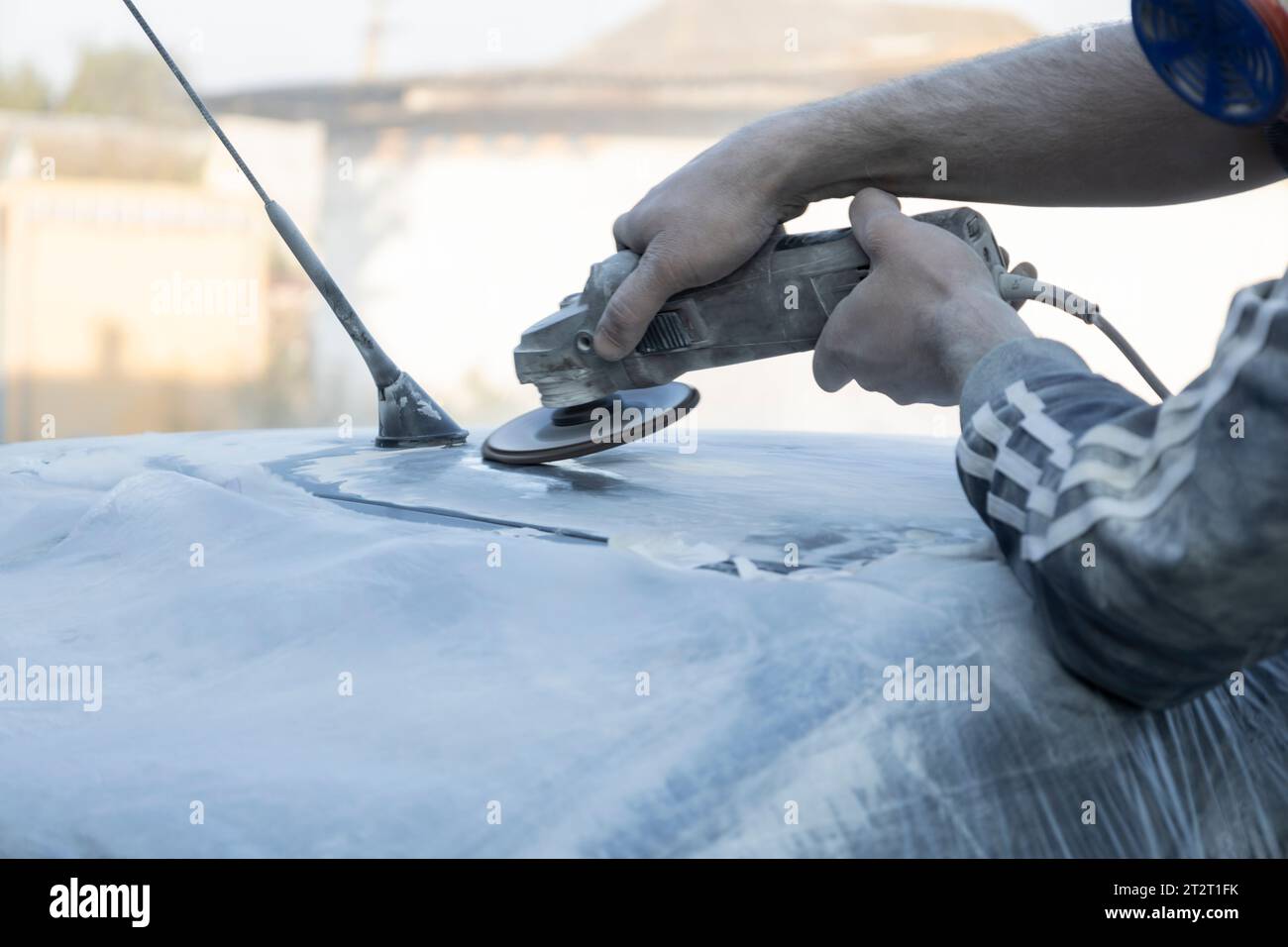 Hands of the auto repairman grinding roof of the car. Stock Photo