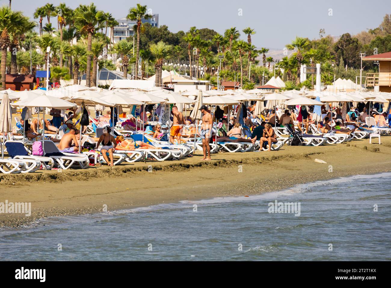 Tourists sunbathing and swimming on Finikoudes beach, Larnaca, Cyprus Stock Photo