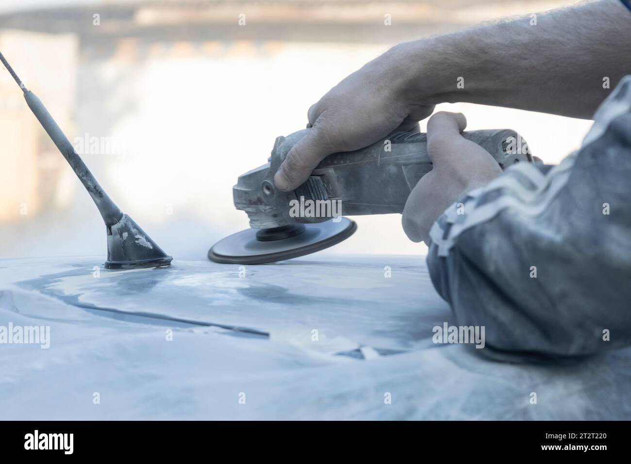 Hands of the auto repairman grinding roof of the car. Stock Photo