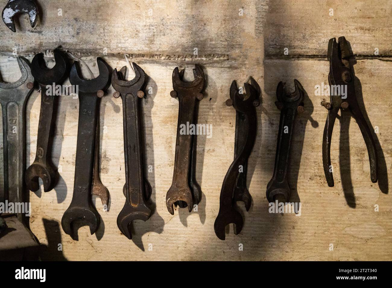 Old wrenches on wooden industrial wall. Tool on the wall of a locksmith against  old grunge background Stock Photo